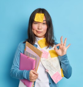 everything is control serious self confident young asian woman makes okay gesture agrees collaborate with colleague preparing research work surrounded with papers stickers